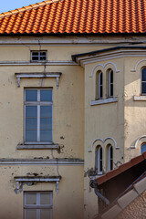 an old manor house. The roof is covered with red tiles and the plaster of the house has already visible cracks.