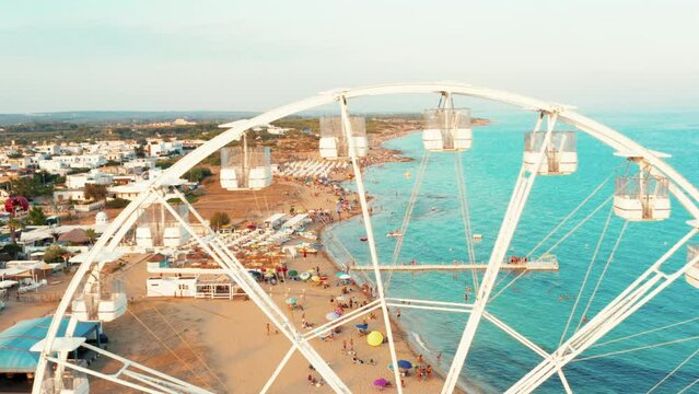 ferris wheel on the beach at sunset in summer - drone view, Salento, Puglia, Campomarino di Maruggio, Italy