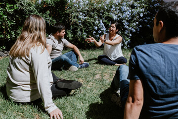 hispanic young people seated in circle on grass and participating at group therapy session in Mexico Latin America	