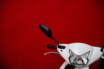 Fototapeta na wymiar Modern scooter front side, against a red wall