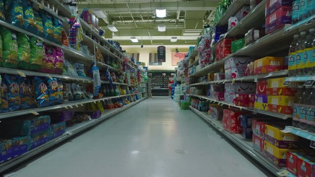 Backwards revealing of goods arranged on shelves. Fly in empty shop. Interior of large supermarket outside opening hours