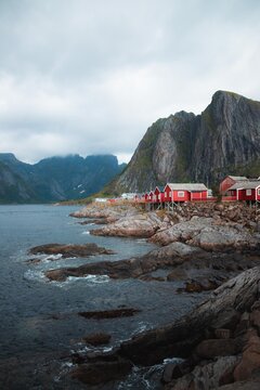 Fjords of Norway vertical wallpaper. Hamnoy, Reine in Lofoten islands in Norway. Moody weather, red cabins with fjords