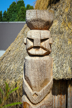 Figura mapuche tallada en madera al frente de una ruca