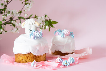 Easter cake with white icing and blue meringues Easter decorative lamb on a pink background with spring cherry blossoms and copy space. Easter Ukraine orthodox sweet bread. Easter card concept.
