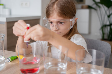 Obraz na płótnie Canvas girl child have fun engaged in chemistry lab activity at home alone.l Teenage kid play laboratory game on table, make experiments feel playful.