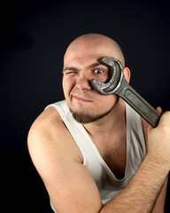 The plumber gets to work. He has a very large wrench. A man with a beard