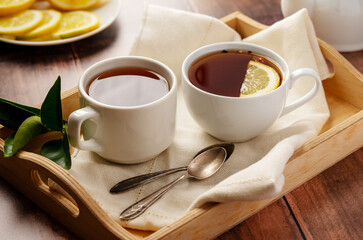 Tea for two. Black tea in white, ceramic cups. Wooden background