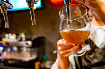 woman bartender hand at beer tap pouring a draught beer in glass serving in a restaurant or pub