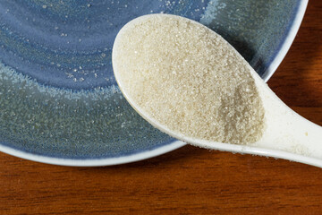 A spoonful of white sugar on a blue plate