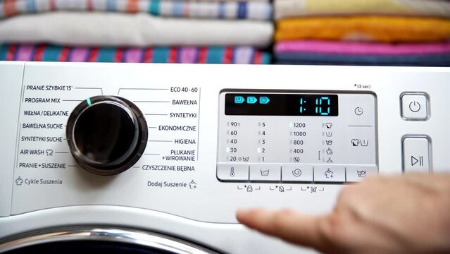 The man presses a button to set the appropriate wash temperature.