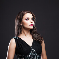 Gorgeous young brunette in a chic evening look. Scarlet lips and eye shadow, wave hair styling