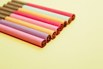 Multicolored cigarettes on a paper background, the concept of a bad habit.