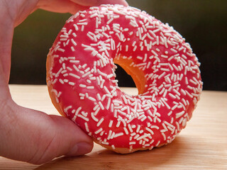 Pink delicious donut in the male hand