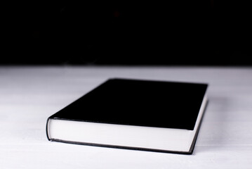 The black book of the Bible lies on the table. On the background