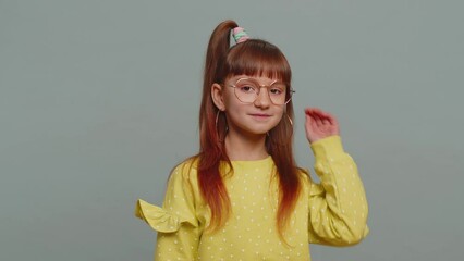 Cheerful lovely young preteen child girl kid in glasses smiling, looking at camera. Little funny female toddler children schoolgirl isolated portrait alone on studio gray background. Childhood
