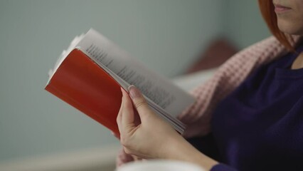 Woman runs through pages of book looking for certain part of story. Hands of female reader holding textbook on blurred background in room closeup