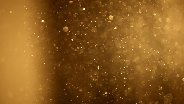 Shining golden particles abstract background. Gold dust particles fly in the air. Glimmering glowing gold bokeh background. Magical fairy background