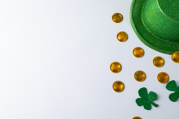 Green hat, golden coins and shamrocks decorations with copy space on white background