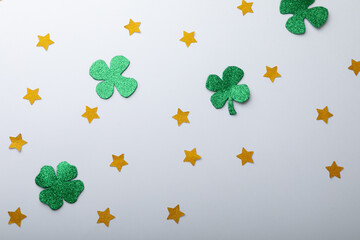 Obraz premium Green shamrocks and golden stars decorations with copy space on white background