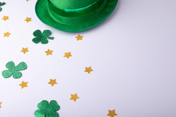 Fototapeta premium Green hat, golden stars and shamrocks decorations with copy space on white background