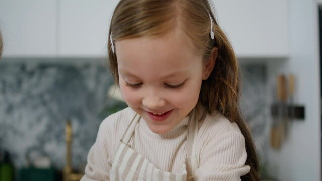 Funny child rolling sleeves up at kitchen portrait. Cute baby baking at home