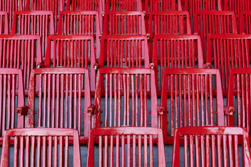 Fototapeta premium Abstract background from elements of red armchairs. Background from rows of red chairs. Lots of red chairs.