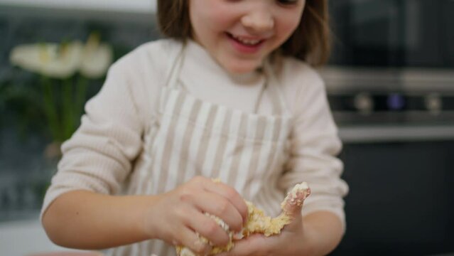 Laughing kid making dough at home portrait. Smiling girl playing with pastry