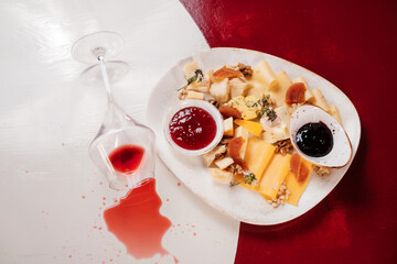 Cheese set with  jam, fruit and nuts. glass with spilled wine