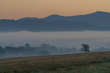 Beautiful sunrise over the mountains in the area of still shaded farmland