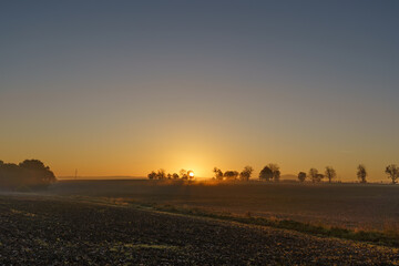 Fototapeta premium Beautiful sunrise over the mountains in the area of still shaded farmland