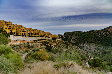 A huge estate with yellow identical buildings on the slope of a mountain rock by the sea