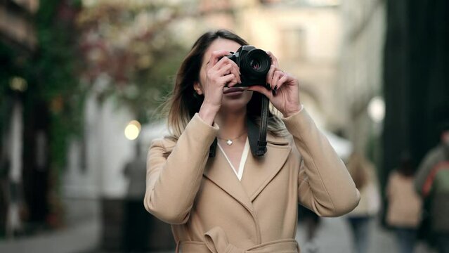 Charming female tourist in stylish wear taking photos during city tour