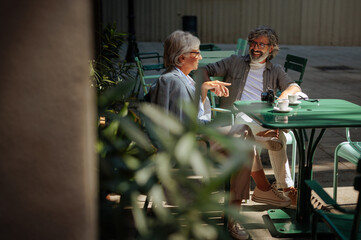 Senior couple drink coffee outside.