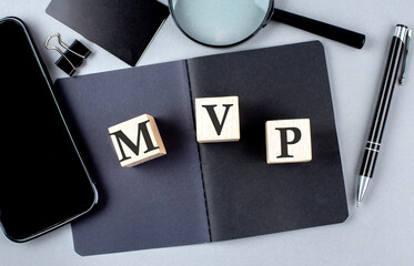Word MVP on wooden block on black notebook with smartpone, credit card and magnifier