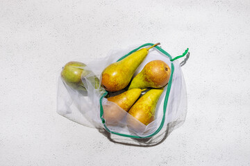 Ripe juicy pears in a packing bag on a white concrete background