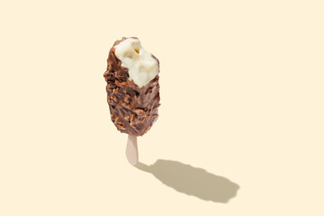 Chocolate ice cream on a stick on yellow pastel background