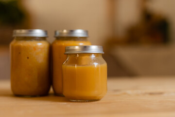 baby vegetable and fruit puree in jars in the kitchen, mockup. Baby food, space for text. Jars of baby food on a wooden table
