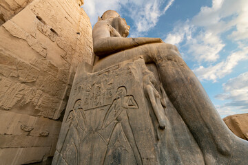 Low angle view of the granite statue of Ramses or Ramesses II seated on a throne with hieroglyphs at the Temple of Luxor, in Luxor Egypt. - obrazy, fototapety, plakaty