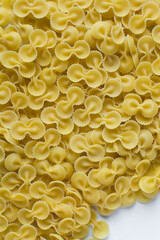 Top view of Farfalle tonde pasta shells on a table, dry uncooked Farfalle tonde