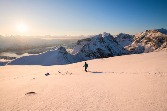 Female hiker descending snowy hillside from summit or Ryten, Moskenes&Atilde;&cedil;y, Lofoten Islands, Norway
