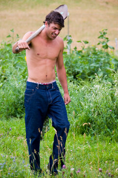 Male with his shirt off and shovel over his shoulder makes his way across the aisles at an organic farm in Victor, Idaho.