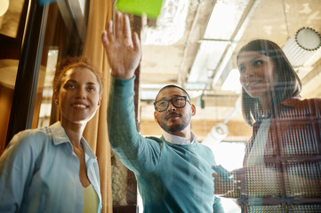 Colleagues working on business goals using glass board at coworking space