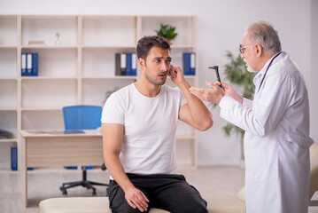 Young male doctor visiting old doctor otolaryngologist