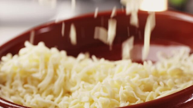 Grated pizza cheese mozarella close up, chef hand touching cheese for Italian pasta or pizza. Macro close up of cheddar cheese.