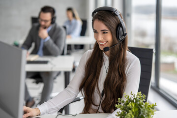 Portrait of young beautiful woman with headset working at call center in modern office. - obrazy, fototapety, plakaty