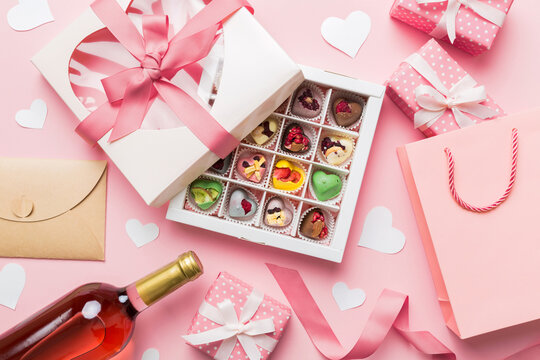 Top View Photo Of St Valentine Day Decor Shopping, Bag, Wine, Bottle, Envelope, Gift, Box, Candy And Red Heart On Colored Background With Empty Space. Frame Background