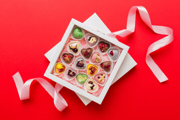 Holiday composition: sweet candy, with gift boxes with bow and chocolate hearts, photo template, background. Top View with copy space on colored background