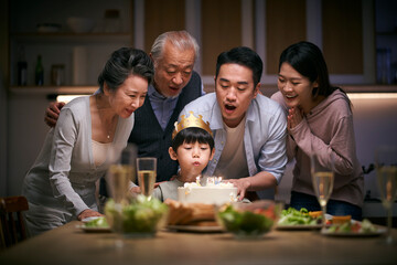 three generation asian family celebrating little boy's birthday at home