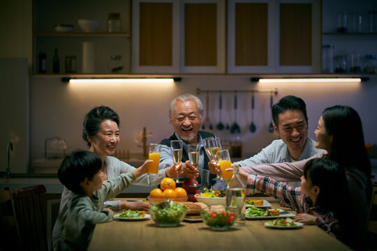 happy three generation asian family toasting while having dinner together