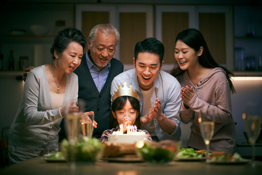 three generation asian family celebrating little girl's birthday at home